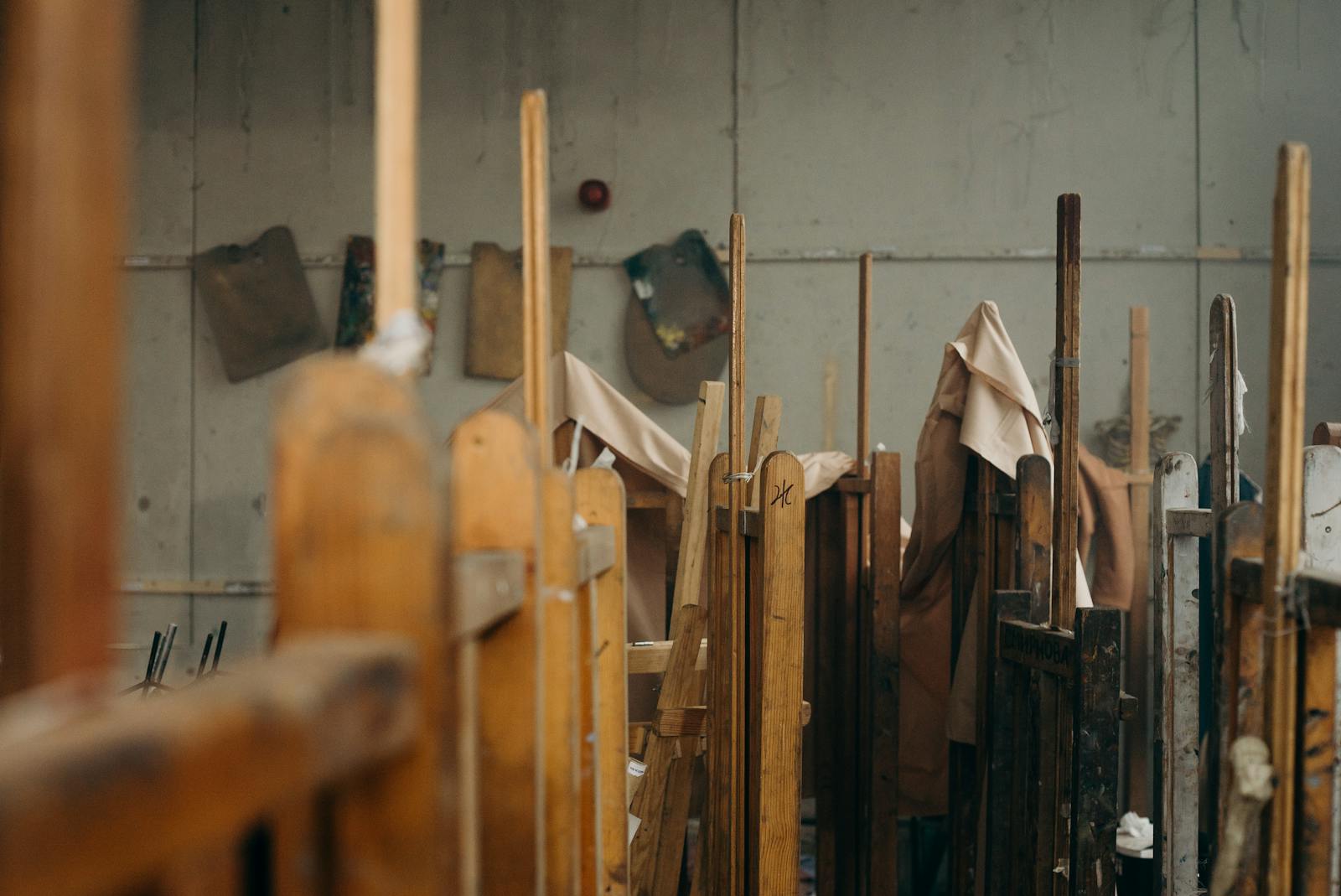 A cozy art studio displaying wooden easels and canvases covered with cloth, inviting creativity.